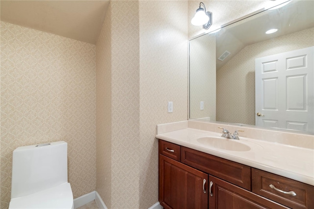 bathroom featuring vanity, toilet, and lofted ceiling