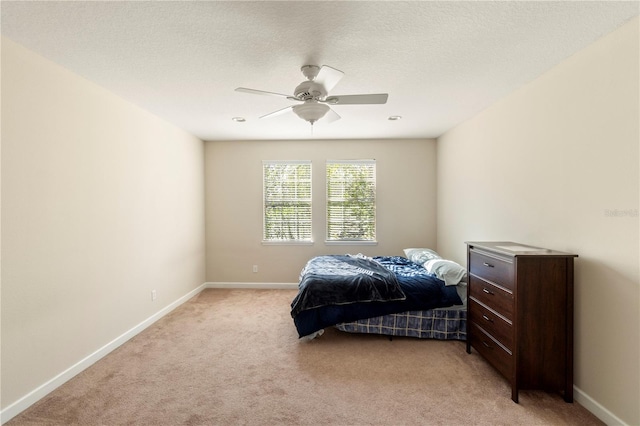 bedroom with a textured ceiling, ceiling fan, and light carpet