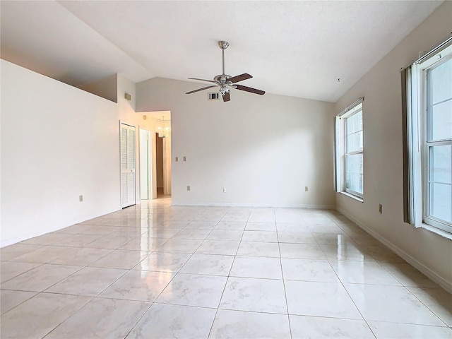 tiled empty room with ceiling fan and vaulted ceiling