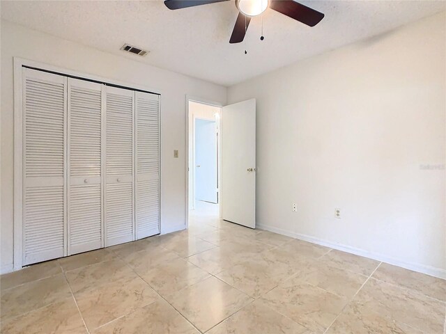 unfurnished bedroom with ceiling fan and a closet