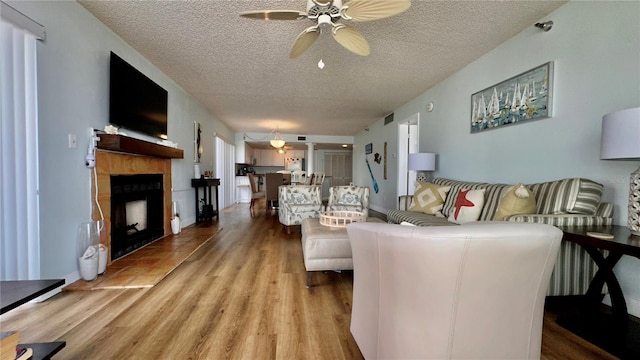 living room with a healthy amount of sunlight, ceiling fan, light hardwood / wood-style floors, and a textured ceiling