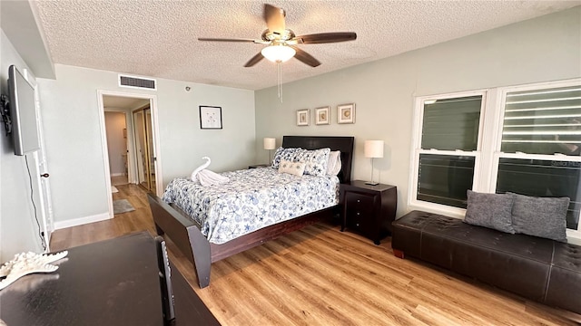 bedroom featuring ceiling fan, light hardwood / wood-style floors, and a textured ceiling