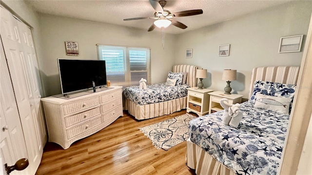 bedroom featuring a textured ceiling, light wood-type flooring, a closet, and ceiling fan