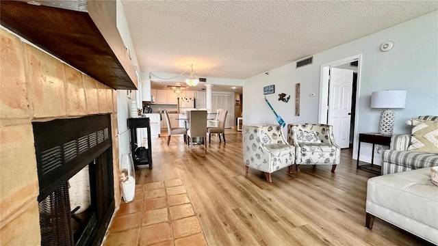 living room with a textured ceiling, light hardwood / wood-style floors, and an inviting chandelier