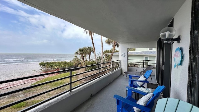 balcony with a water view and a view of the beach