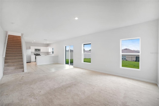 unfurnished living room featuring plenty of natural light and light carpet