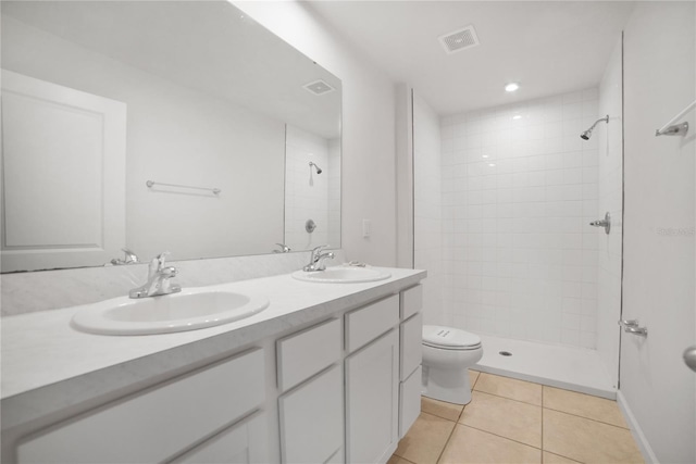 bathroom featuring tile patterned flooring, vanity, tiled shower, and toilet