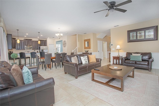 tiled living room featuring ceiling fan with notable chandelier