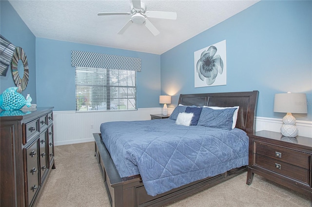 bedroom with a textured ceiling, light colored carpet, and ceiling fan