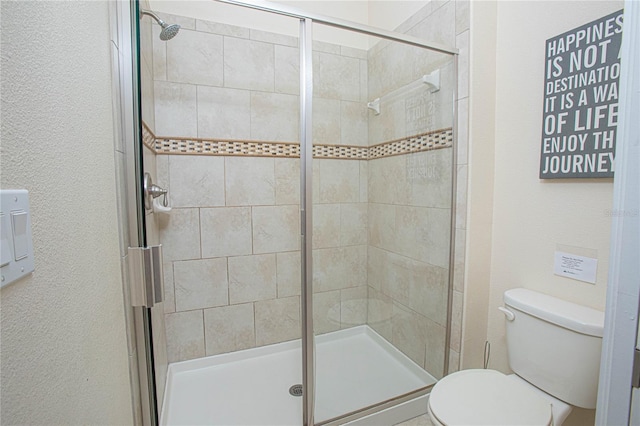 bathroom with a shower with shower door and toilet