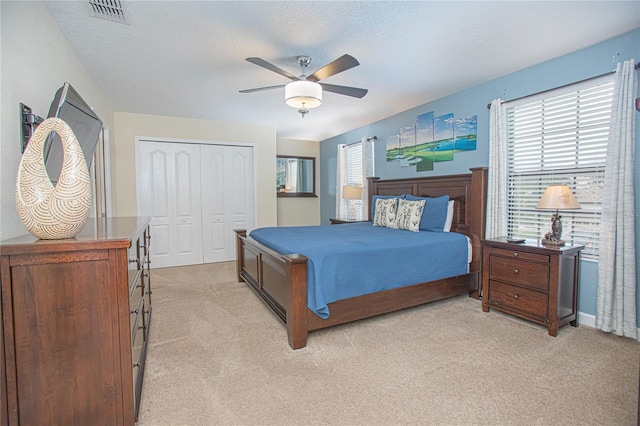 carpeted bedroom featuring ceiling fan, a textured ceiling, and a closet