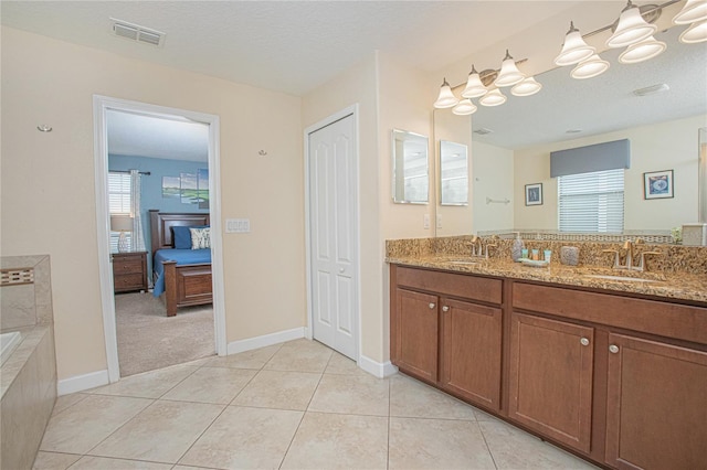 bathroom featuring tile patterned flooring, a textured ceiling, vanity, and a relaxing tiled tub