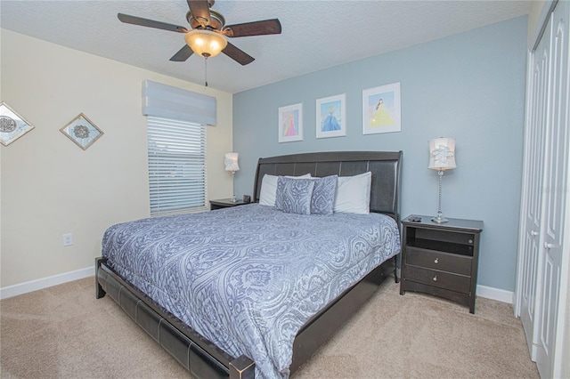 bedroom featuring ceiling fan, light colored carpet, a textured ceiling, and a closet