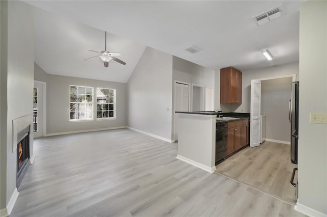 kitchen featuring ceiling fan, dishwasher, stainless steel fridge, vaulted ceiling, and light wood-type flooring