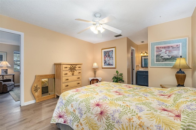 bedroom with hardwood / wood-style floors, ensuite bathroom, and ceiling fan