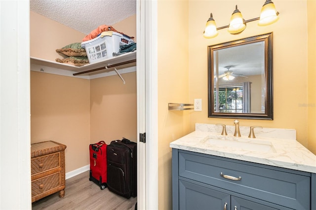 bathroom featuring ceiling fan, vanity, a textured ceiling, and hardwood / wood-style flooring