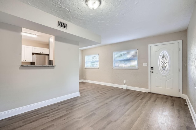 entryway featuring light hardwood / wood-style flooring and a textured ceiling