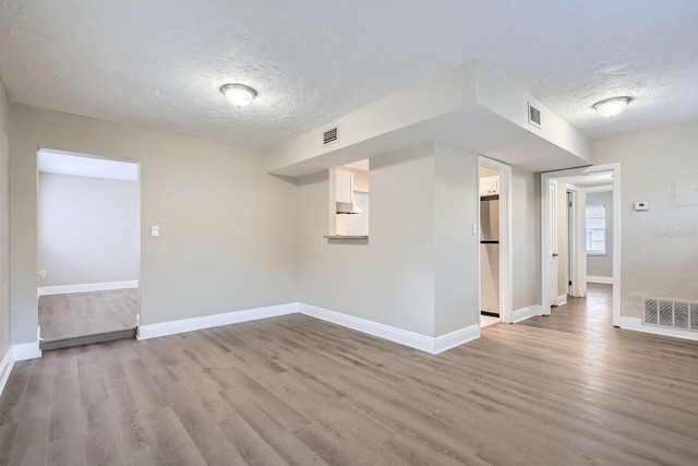 unfurnished room featuring light hardwood / wood-style flooring and a textured ceiling