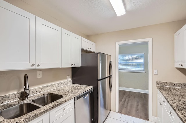 kitchen featuring white cabinetry, sink, stone counters, and appliances with stainless steel finishes