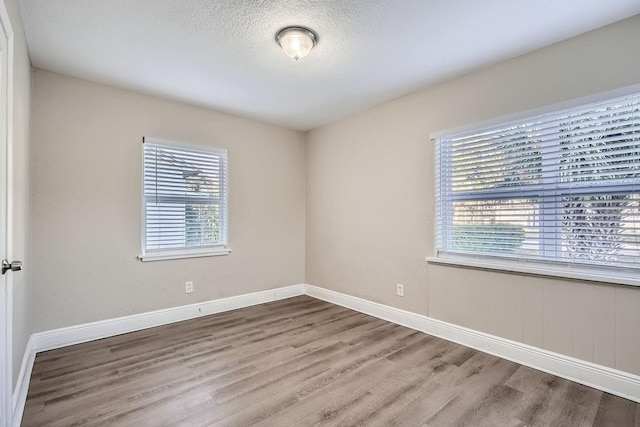 unfurnished room with plenty of natural light, hardwood / wood-style floors, and a textured ceiling