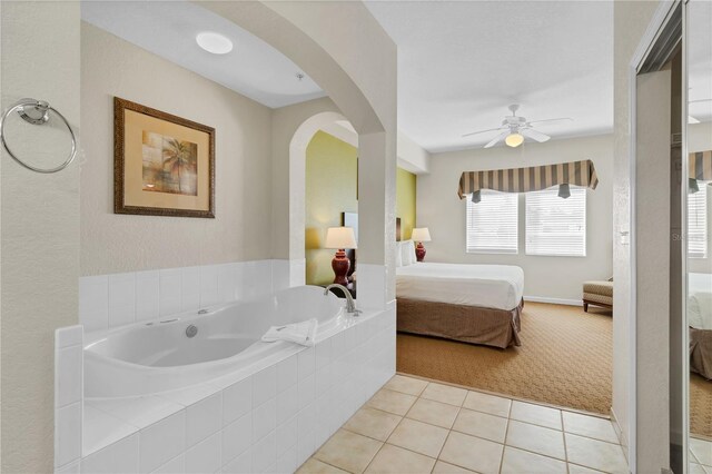 bathroom with tiled tub, tile patterned floors, and ceiling fan