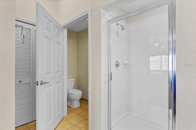 bathroom with a shower with shower door, tile patterned floors, and toilet