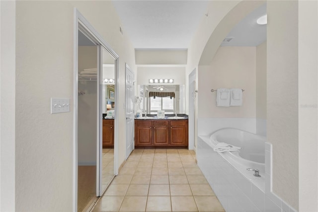 bathroom featuring a relaxing tiled tub, tile patterned floors, and vanity