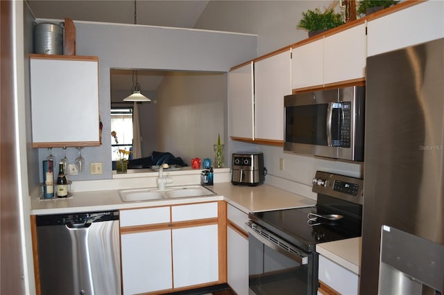 kitchen with decorative light fixtures, stainless steel appliances, white cabinetry, and sink