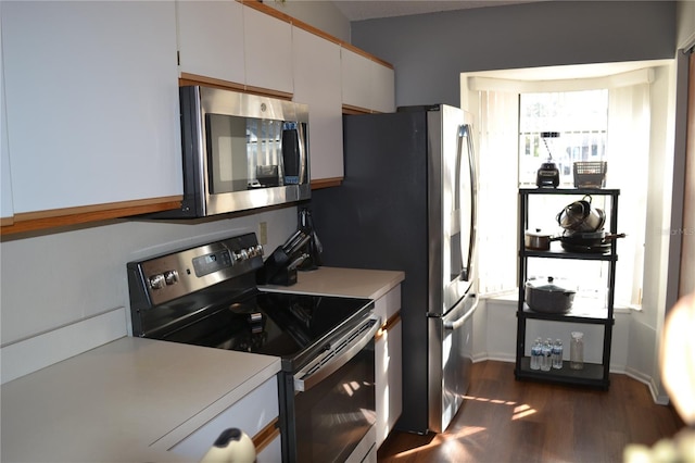 kitchen with appliances with stainless steel finishes, white cabinetry, and dark wood-type flooring