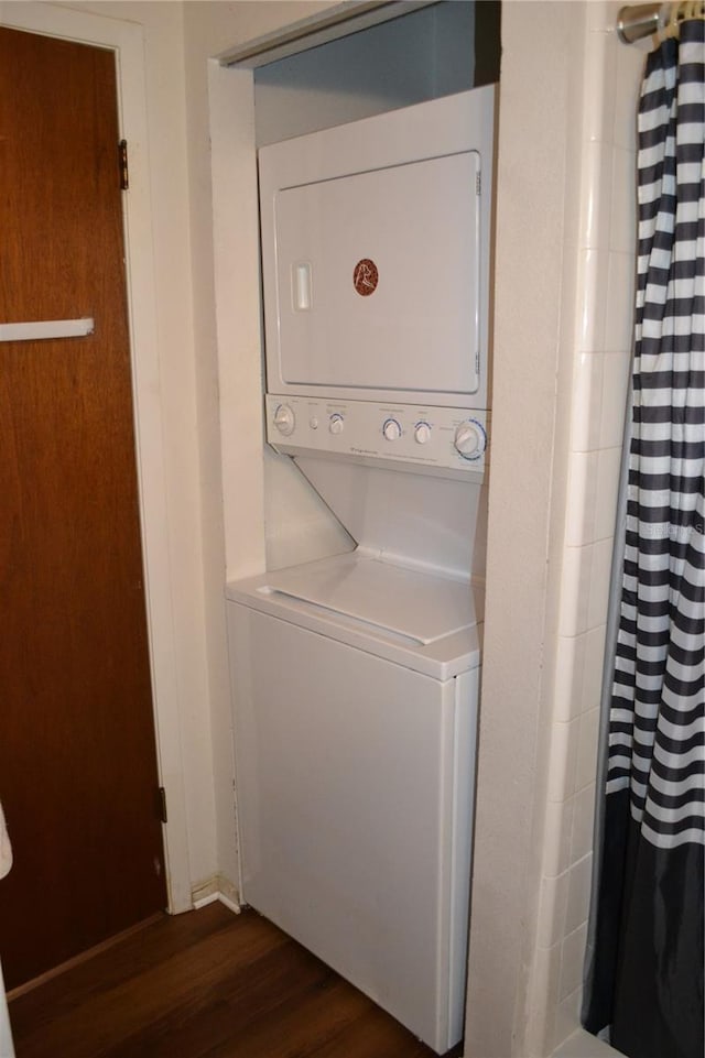 laundry room with stacked washer / dryer and dark wood-type flooring