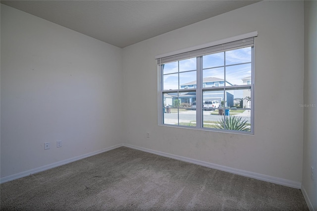 carpeted spare room featuring baseboards