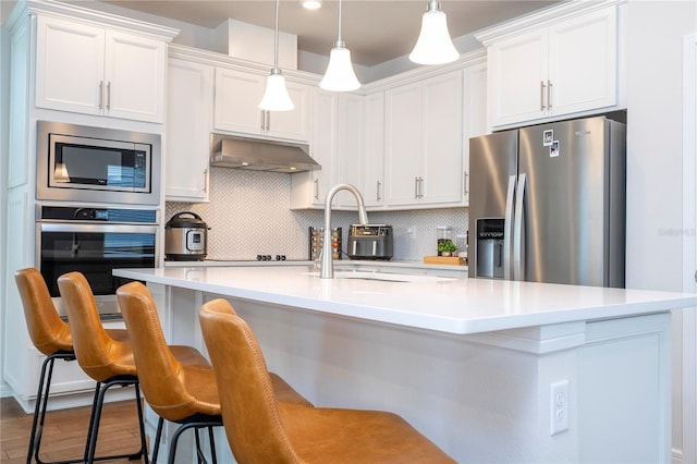 kitchen featuring stainless steel appliances, white cabinetry, and a kitchen island with sink