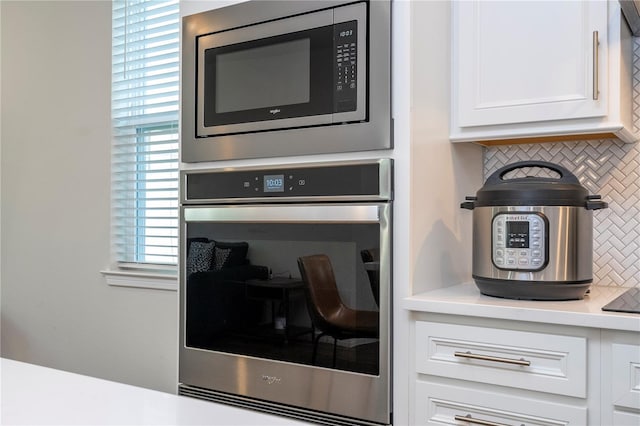 interior details featuring tasteful backsplash, white cabinetry, and stainless steel appliances