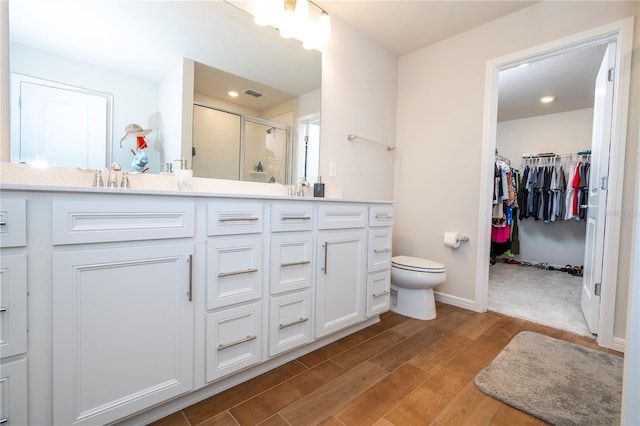 bathroom featuring a shower with door, vanity, and toilet