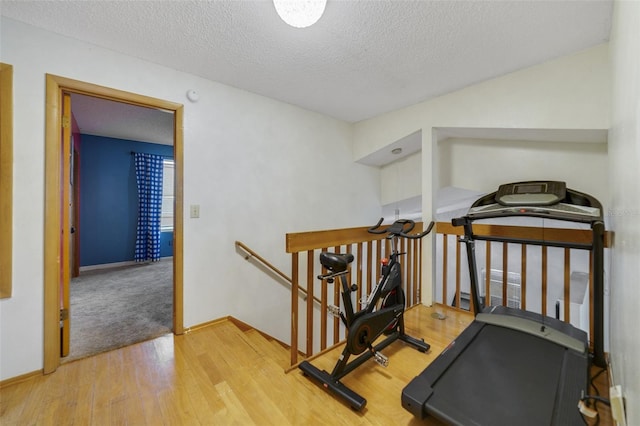 exercise room with hardwood / wood-style floors and a textured ceiling