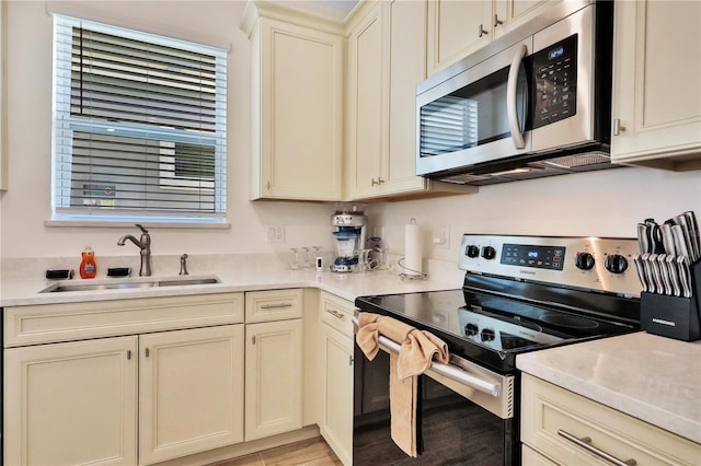 kitchen featuring stainless steel appliances, sink, and cream cabinetry