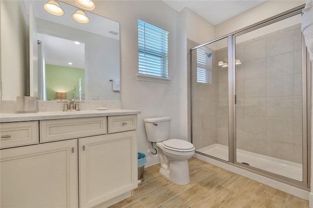 bathroom featuring a shower with door, vanity, and toilet