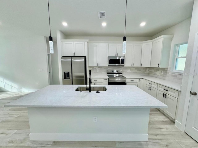 kitchen featuring decorative light fixtures, stainless steel appliances, white cabinetry, and sink