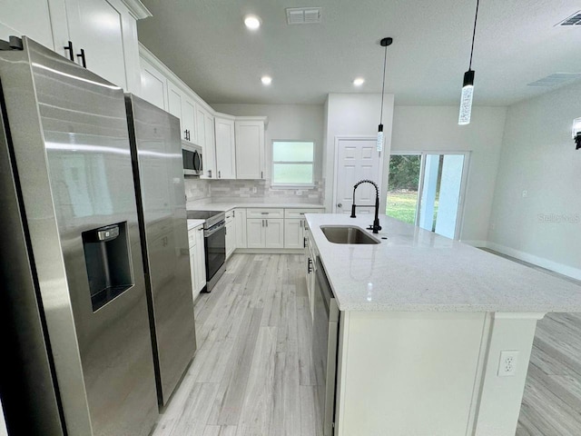 kitchen featuring stainless steel appliances, a kitchen island with sink, sink, white cabinets, and hanging light fixtures