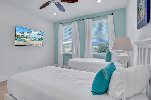 bedroom featuring ceiling fan, multiple windows, and light wood-type flooring