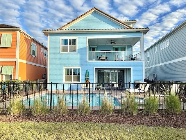 back of property with a balcony, a fenced in pool, ceiling fan, and a patio