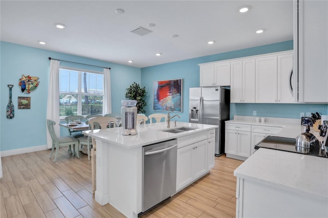 kitchen with appliances with stainless steel finishes, white cabinets, a center island with sink, and sink