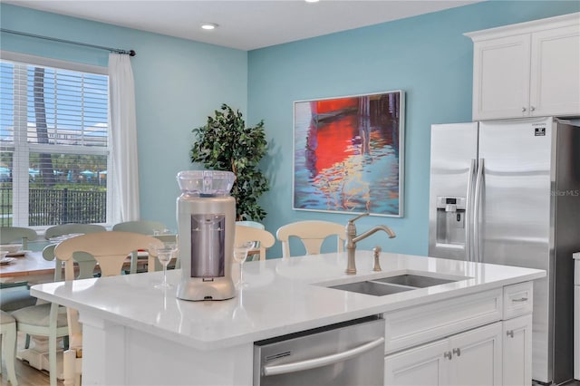 kitchen with a center island with sink, appliances with stainless steel finishes, white cabinetry, and sink