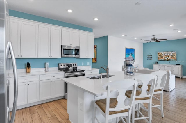 kitchen with white cabinetry, an island with sink, ceiling fan, appliances with stainless steel finishes, and sink