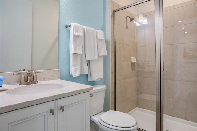 bathroom featuring toilet, vanity, and a shower with door