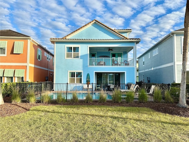 back of house with a balcony, a pool, a yard, and ceiling fan