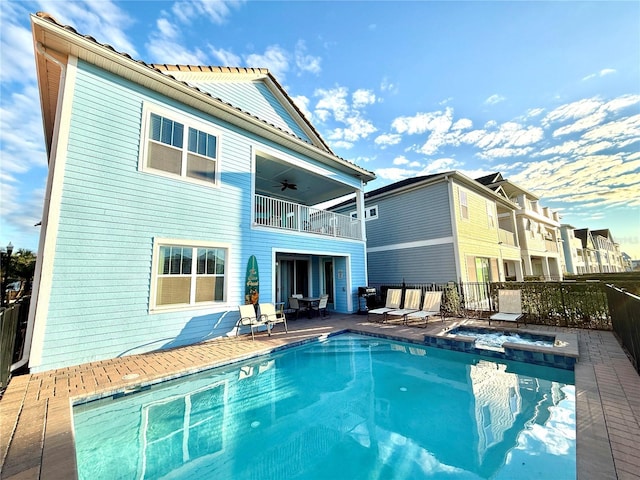 rear view of property with a pool with hot tub, a patio, a balcony, and ceiling fan