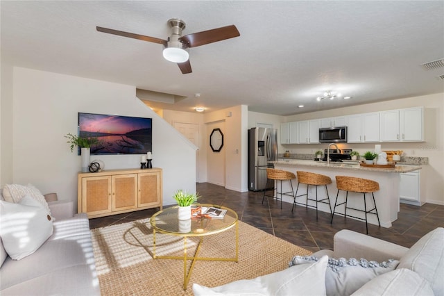 living room featuring sink, a textured ceiling, and ceiling fan