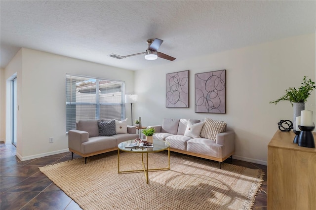 living room featuring ceiling fan and a textured ceiling