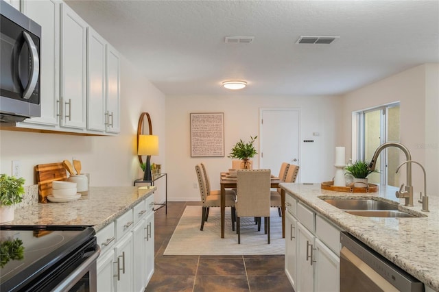 kitchen with white cabinetry, sink, light stone counters, and stainless steel appliances